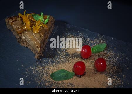 Pezzo di torta con cioccolato e delicato crema di limone e fragole. Un bicchiere di vino rosso con fragole e arance in comune con una persona cara Foto Stock