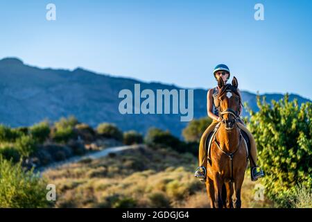 Giovane donna che ama andare a cavallo nella natura montagnosa dell'Andalusia, Spagna Foto Stock