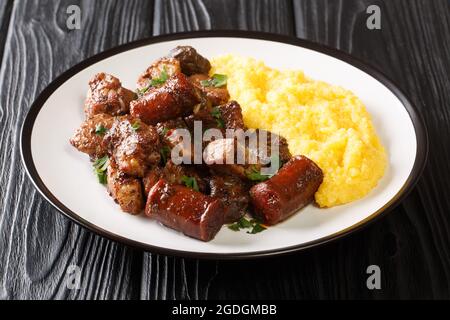 Delizioso maiale fritto, salsicce e frattaglie con aglio servito con porridge di mais primo piano in un piatto sul tavolo. Orizzontale Foto Stock