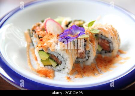 tonno al salmone e uramaki all'avocado con salsa piccante in primo piano Foto Stock
