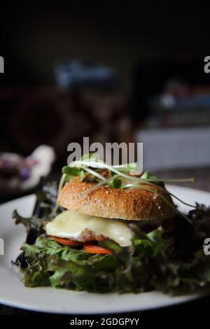 bagel con bistecca e formaggio su fondo di legno Foto Stock