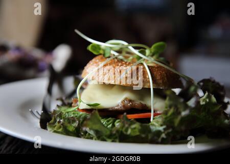 bagel con bistecca e formaggio su fondo di legno Foto Stock