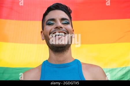 Felice uomo omosessuale che celebra l'orgoglio gay che tiene la bandiera arcobaleno simbolo della comunità LGBTQ Foto Stock