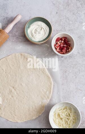 Fare un tarte flambee (flammkuchen) con crema fraiche, fromage blanc, larcon e cipolla. Foto Stock