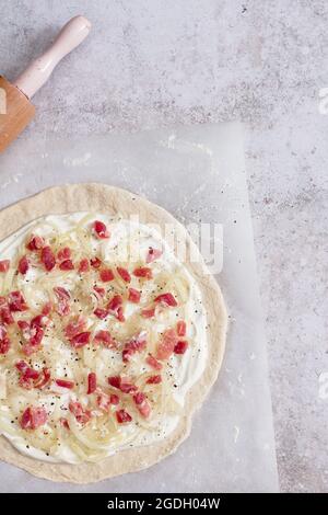 Preparazione di un tarte flambee (flammkuchen) con crema fraiche, fromage blanc, larcon e cipolle. Foto Stock