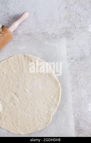 Pasta di pane o pasta di pizza che viene arrotolata con un mattonello per fare tarte flambee o flammkuchen. Foto Stock
