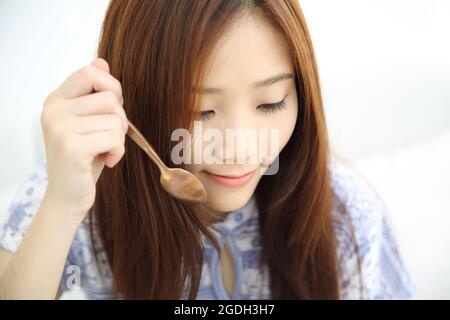 Giovane donna asiatica che mangia ghiaccio rasato con latte e cocco Foto Stock