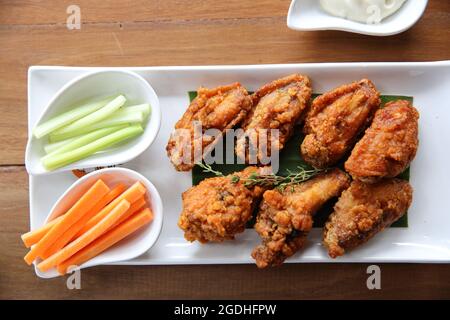 Ali di bufalo pollo barbecue con carote e cetrioli su sfondo di legno Foto Stock