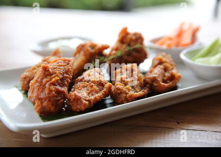 Ali di bufalo pollo barbecue con carote e cetrioli su sfondo di legno Foto Stock