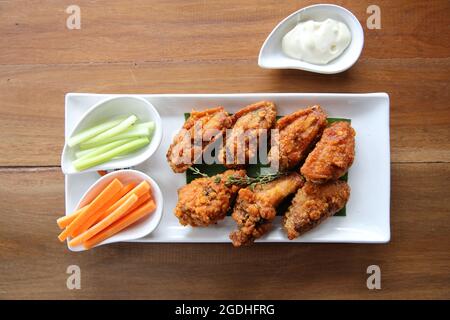 Ali di bufalo pollo barbecue con carote e cetrioli su sfondo di legno Foto Stock