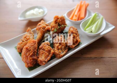 Ali di bufalo pollo barbecue con carote e cetrioli su sfondo di legno Foto Stock