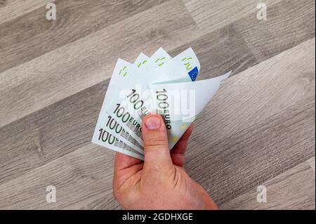 mano di uomo che conta 100 banconote in euro su tavola di legno Foto Stock