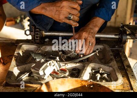 Waisai, Indonesia - 16 ottobre 2019: Un uomo, che lavora come meccanico, ripara abilmente il carburatore di un motore di barca nella sua officina Foto Stock