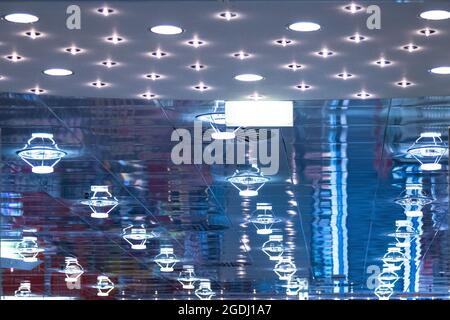 Le lampade da soffitto si riflettono nel vetro, creando una luce blu con molte strutture. Foto Stock