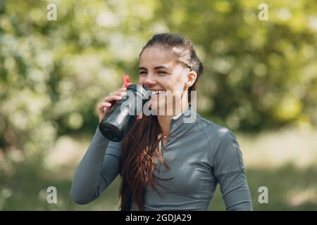 Stanca donna runner jogger bere acqua in bottiglia dopo jogging Foto Stock