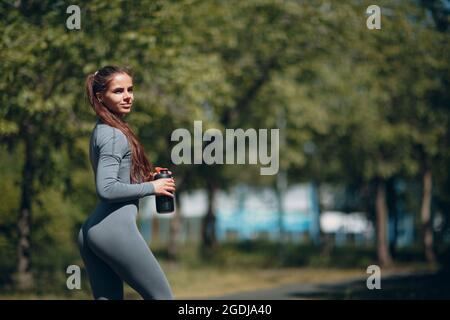 Stanca donna runner jogger bere acqua in bottiglia dopo jogging Foto Stock