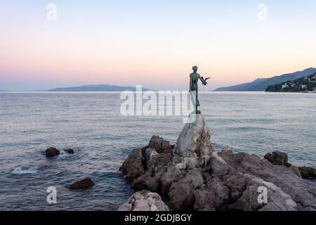 "maiden with a Seagull", una famosa statua che si erge su una roccia vicino alla passeggiata costiera della città turistica croata di Opatija. Scatto serale. Foto Stock