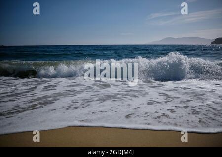 Onde che si infrangono sulla spiaggia sabbiosa di Mylopotas in iOS Grecia Foto Stock
