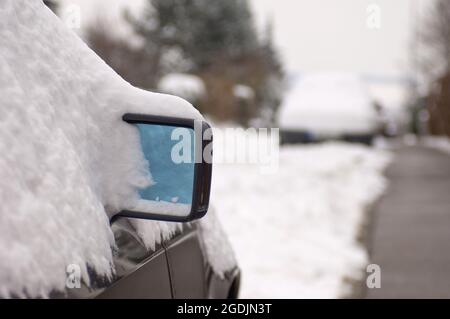 Auto coperta di neve sul lato della strada, specchio retrovisore in direzione di neve, Germania Foto Stock