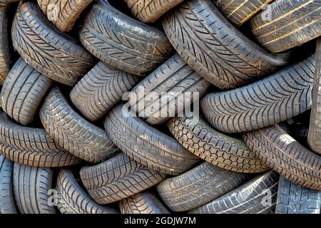 Vecchi pneumatici usati di automobili e camion in un mucchio. Pronto per il riciclaggio o lo smaltimento della gomma Foto Stock