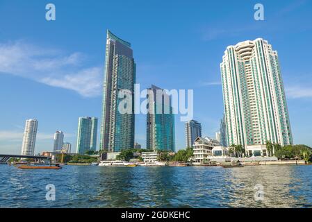 BANGKOK, THAILANDIA - 01 GENNAIO 2019: Edifici alti e moderni sulle rive del fiume Chao Phraya in una giornata di sole Foto Stock