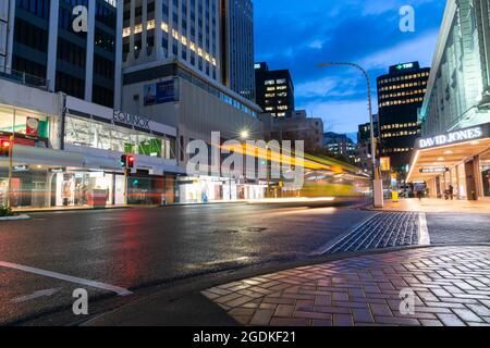 Wellington Nuova Zelanda   Luglio 27 2021; strade scintillanti e flussi di traffico di passaggio nel quartiere degli affari del centro cittadino con autobus illuminato Foto Stock