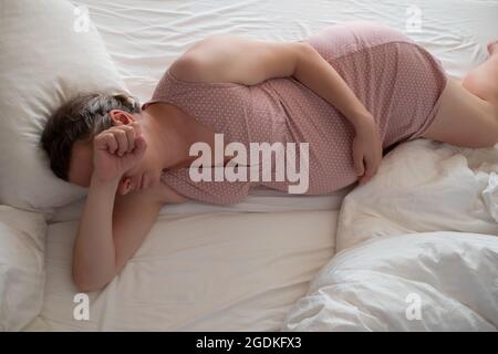 Donna incinta preoccupata nel letto che soffre di insonnia Foto Stock