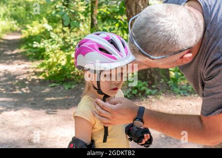 papà mette su figlia sportswear protettivo. Foto Stock