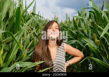 Donna ridente in piedi nel campo di mais Foto Stock