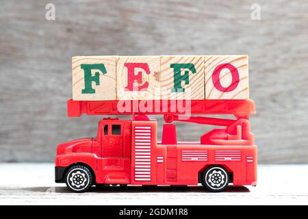 Giocattolo a scala antincendio camion tenere il blocco di lettere in parola FEFO (prima espirata prima fuori) su sfondo di legno Foto Stock