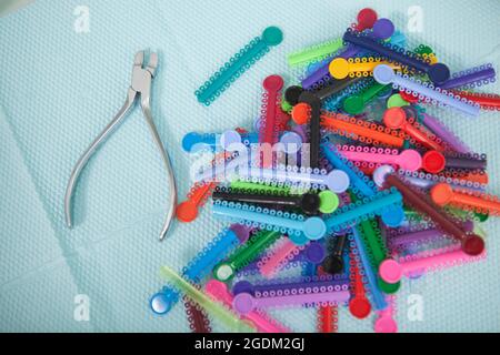 Primo piano di molti bretelle colorate elastici e dentisti strumento su sfondo blu Foto Stock