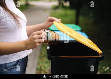 Primo piano ritratto donna lancio a mano vuota bottiglia d'acqua di plastica in contenitore di riciclaggio Foto Stock