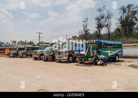 ANTIGUA, GUATEMALA - 28 MARZO 2016: I colorati autobus di pollo, ex autobus scolastici statunitensi, sono allineati al terminal principale degli autobus nella città di Antigua Guatemala. Foto Stock