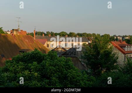 Alba estiva, cinque al mattino. Vista dei tetti di Cēsis dalla finestra del quarto piano. Tetti rossi, vecchi, arrugginiti, vecchie case in legno, lucernario Foto Stock