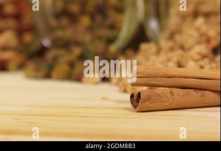 Bastoncini alla cannella con vasi di granola e noci in background Foto Stock