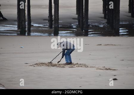 L'uomo con il rivelatore di metalli su una spiaggia Foto Stock