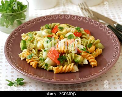 Insalata di pasta. Spirali con verdure, surimi e avocado. Con foglie di basilico come condimento. Foto Stock