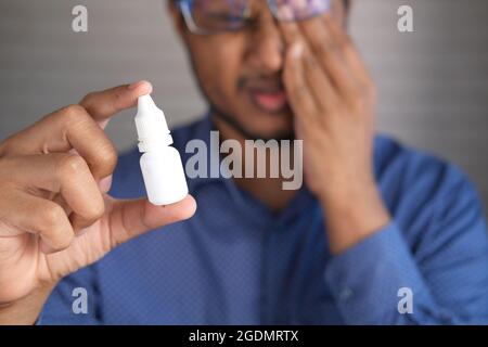 uomo sconvolto che soffre di forte dolore agli occhi e di tenere un occhio goccia Foto Stock