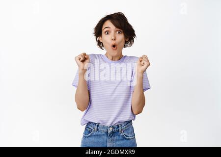 Ritratto di cute sorpresa ragazza guardare eccitato e senza parole, in awe essere vincitore, trionfando, vincendo raggiungere obiettivo, fare WOW faccia, saltando stupito Foto Stock