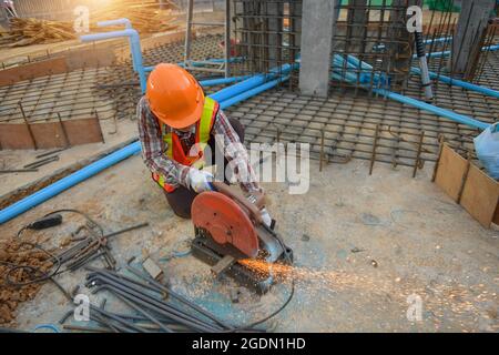 il lavoratore taglia l'acciaio con la macchina da taglio il disco circolare taglia la parte del ferro fino a quando non si formano scintille durante il taglio dell'acciaio. Foto Stock