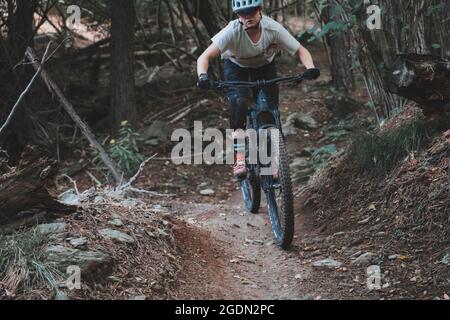 Scatto di azione di una giovane donna che guida una Mountainbike nella foresta Foto Stock