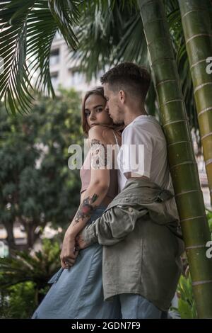 Ritratto di una coppia amorevole che si coccola in un parco. Guardando la fotocamera con spazio per la copia. Indossare abiti casual. Persone eleganti. Foto di alta qualità Foto Stock