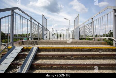 Ponte ferroviario con scalini, con scalini impressionanti in prospettiva. Attraversamento pedonale in alto. Ponte scale che collegano una piattaforma a un'altra presso Foto Stock
