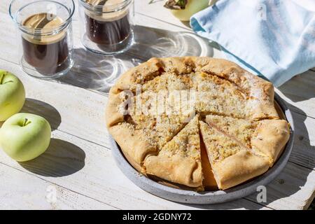Galette di mele con streusel di nocciole, servite con caffè su sfondo di legno. Stile rustico. Foto Stock