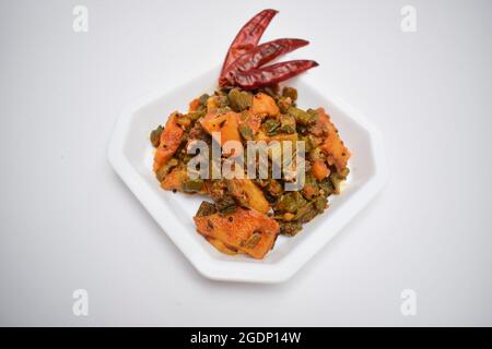 In stile indiano masala sabji o sabzi di bhindi o Okra noto anche come ladyfinger, servito in piatto laterale. ladyfinger con patata guarnita con lime l Foto Stock