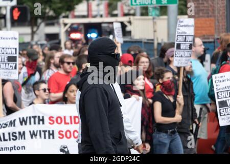 I manifestanti mascherati contro il presidente Trump marciano con striscioni e cartelli a Seattle, USA Foto Stock