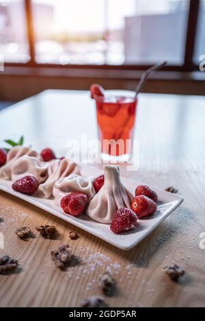 gnocchi dolci o khinkali con fragola e bevanda fredda alla limonata rossa sul tavolo Foto Stock