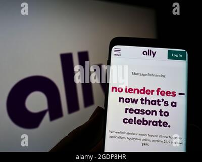 Persona che tiene il cellulare con pagina web della società americana di servizi finanziari Ally Financial Inc. Su schermo con il logo. Mettere a fuoco il centro del display del telefono. Foto Stock