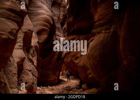 Escursionista passando attraverso le imponenti rocce di Buckskin Gulch nel sud dello Utah Foto Stock