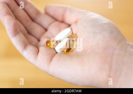 Primo piano di mano con le pillole su di esso. Supplementi con omega, vitamina d, magnesio. Farmaci per il trattamento della malattia Foto Stock